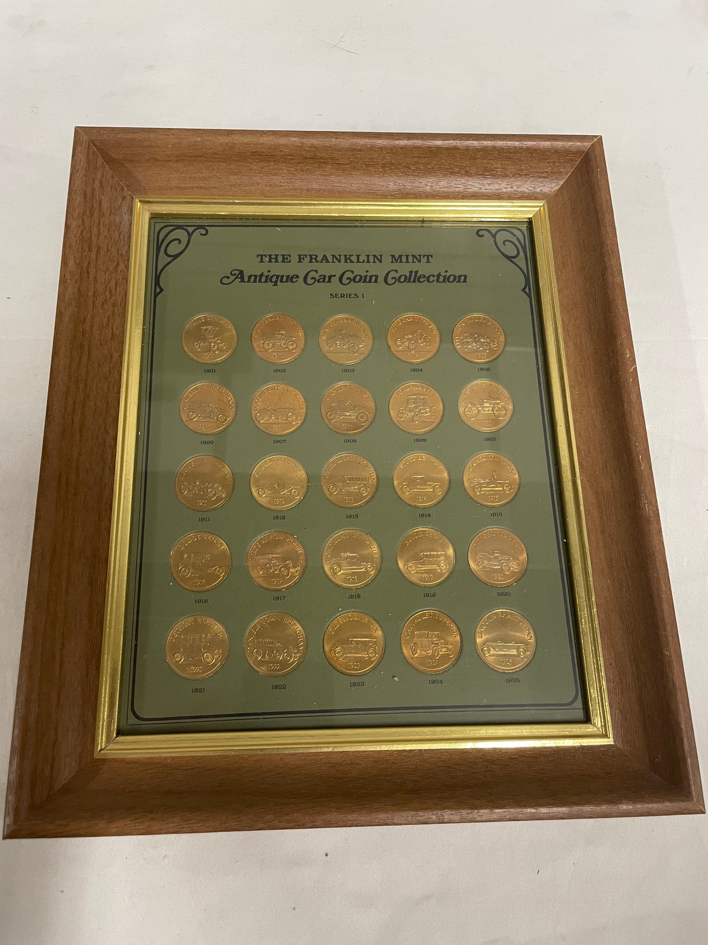 The Franklin Mint Antique Car Coin Collection 10x12in. 1901-1925. Wooden frame included.